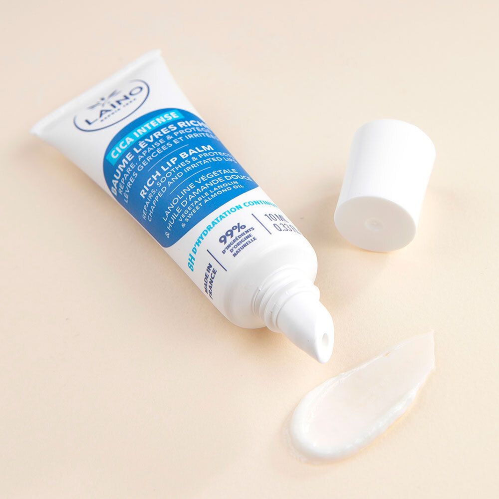 Laino Cica Intense Lippenbalsam-Tube und Produkt. Tube geöffnet, Balsam sichtbar. Weiß, blau und hellbeige.