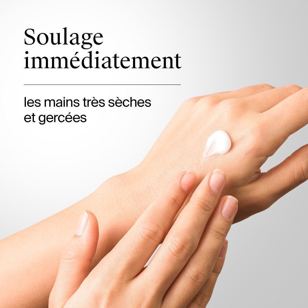 Eine Hand mit einer weißen Creme auf dem Handrücken. Eine zweite Hand reibt die Creme ein.