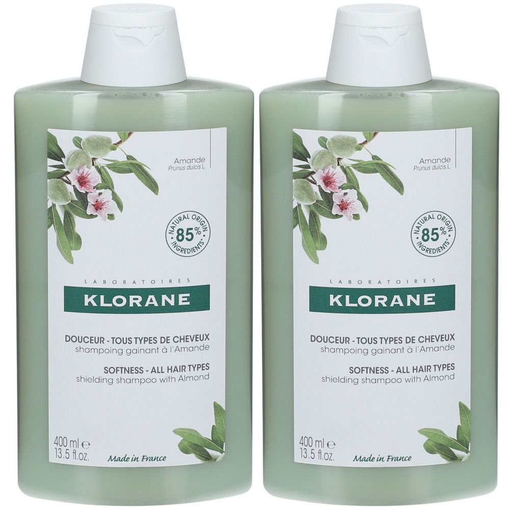 Deux flacons de shampoing verts avec bouchons blancs. Étiquettes avec motif floral et texte: KLORANE, DOUCEUR, SOFTNESS, 400 ml, 85% Natural Origin.