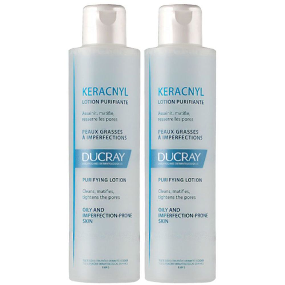 Deux flacons de lotion. Inscription : KERACNYL Lotion Purifiante, Ducray. Pour peaux grasses et à imperfections. Flacons blancs avec étiquette bleue.