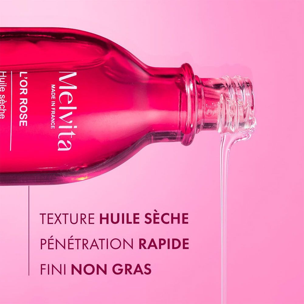 Melvita L'Or Rose Öl wird aus der Flasche gegossen. Text: Texture Huile Sèche, Pénétration Rapide, Fini Non Gras.