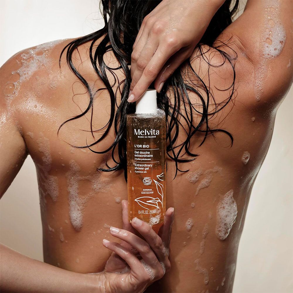Person mit Gel Douche Extraordinaire. Flasche mit Text: L'Or Bio, Gel Douche Extraordinaire.