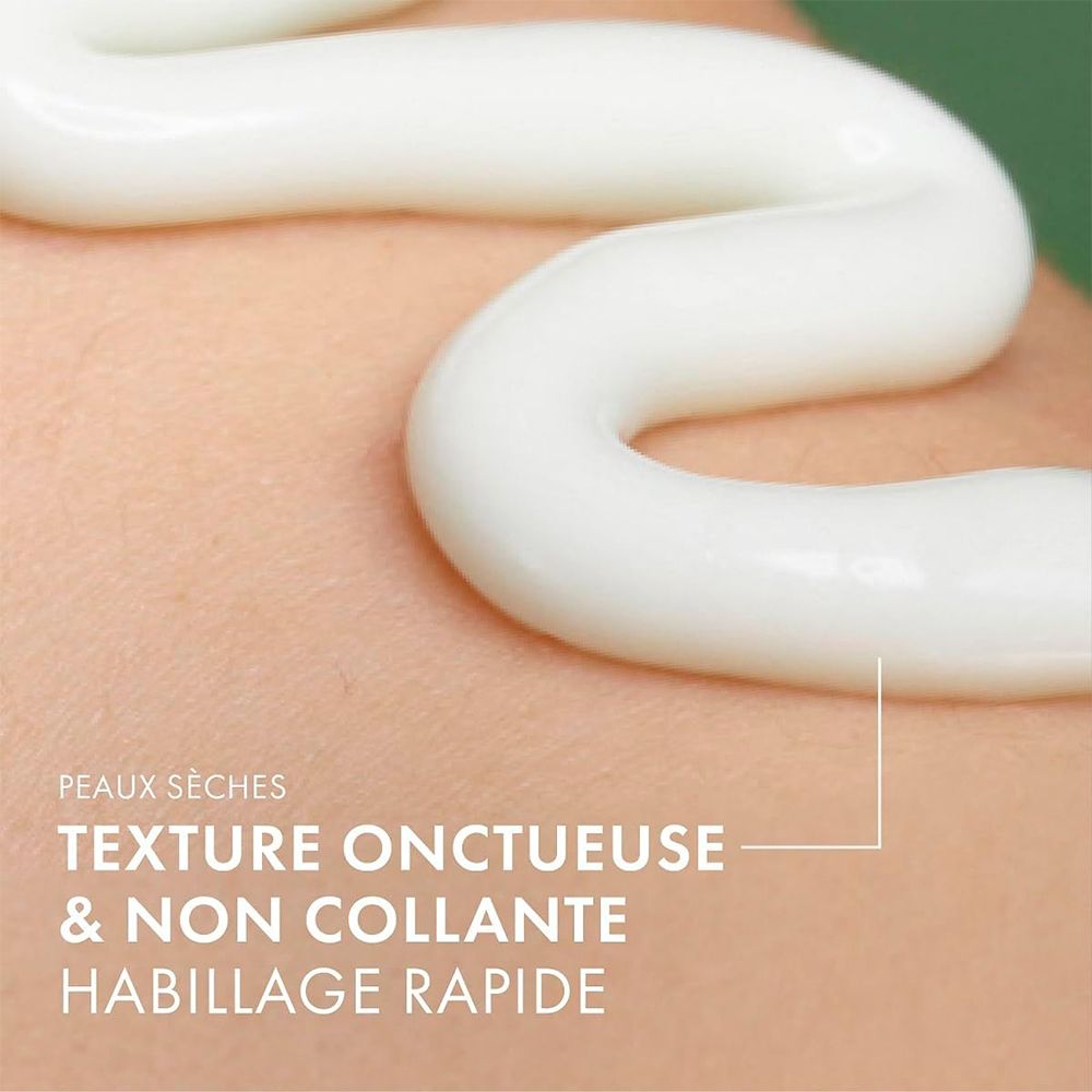 Gros plan de crème sur la peau. Texte : Peaux sèches, texture onctueuse et non collante, habillage rapide.
