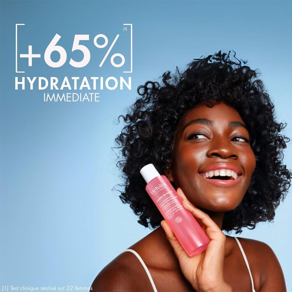 Frau hält eine Rosa-Essenzflasche. Text: +65% Hydratation immédiate.