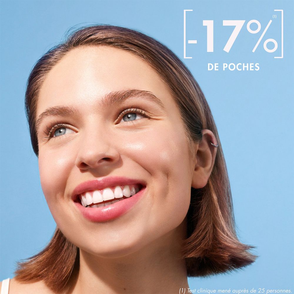 Junge Frau mit strahlendem Lächeln. Text: -17% Tränensäcke.