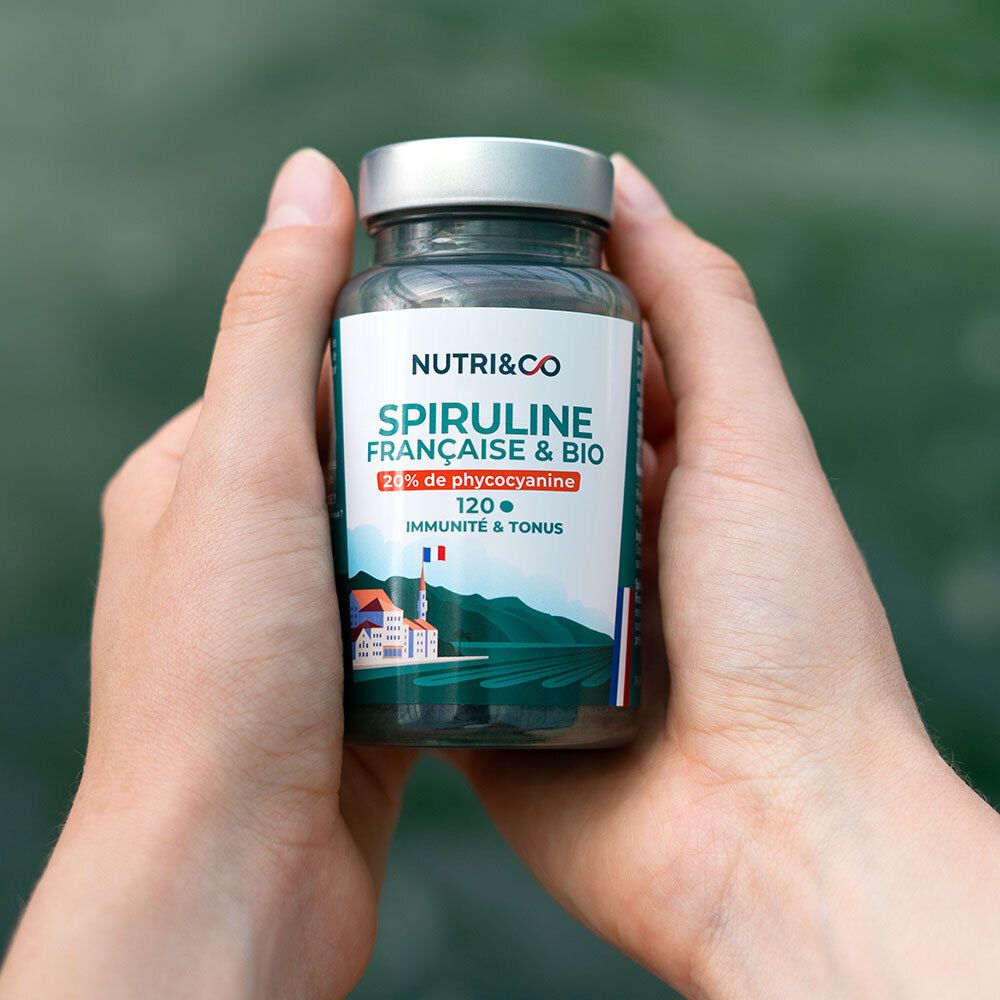 Mains tenant un flacon de Spiruline Française & Bio. 20% phycocyanine, 120 comprimés. Drapeau français.