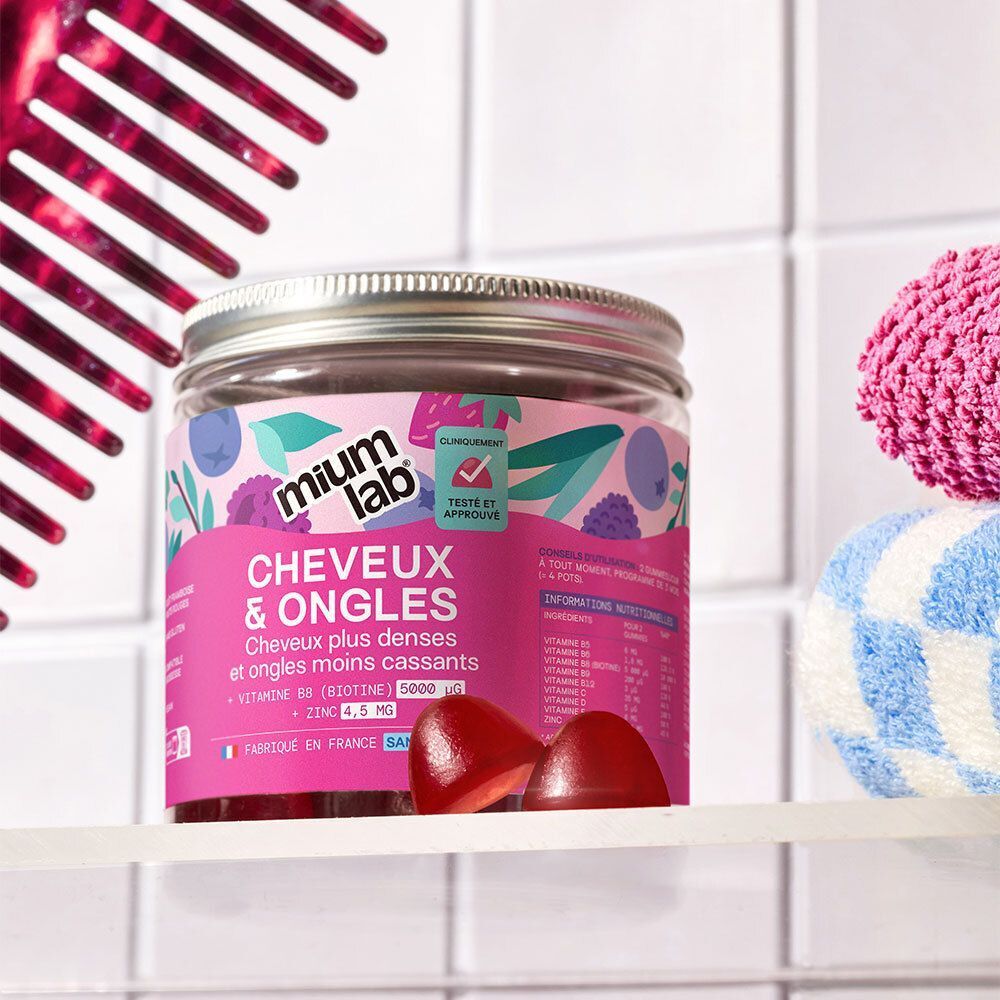 Ein Glas Mium Gummies Haare & Nägel auf einem Regal, mit Kamm und Handtuch.