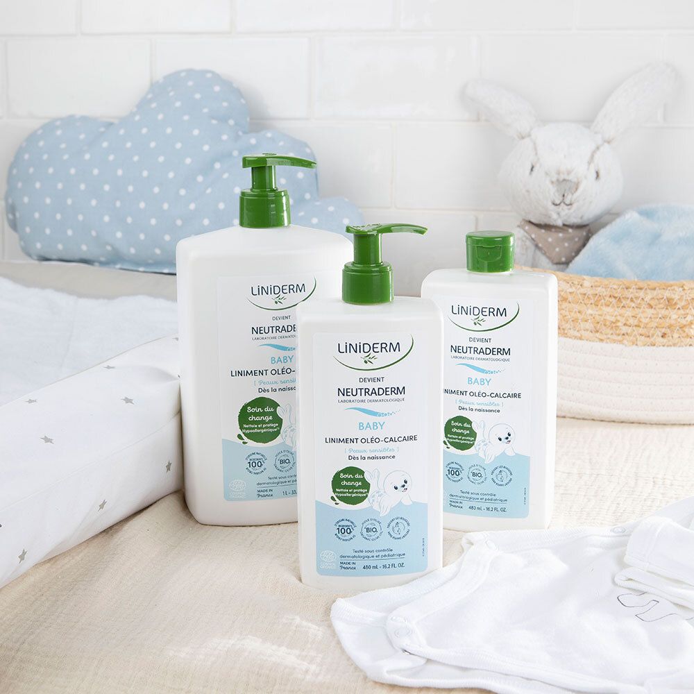 Trois flacons blancs avec pompe verte. Produit : LINIDERM NEUTRADERM BABY. Articles pour bébé en arrière-plan.