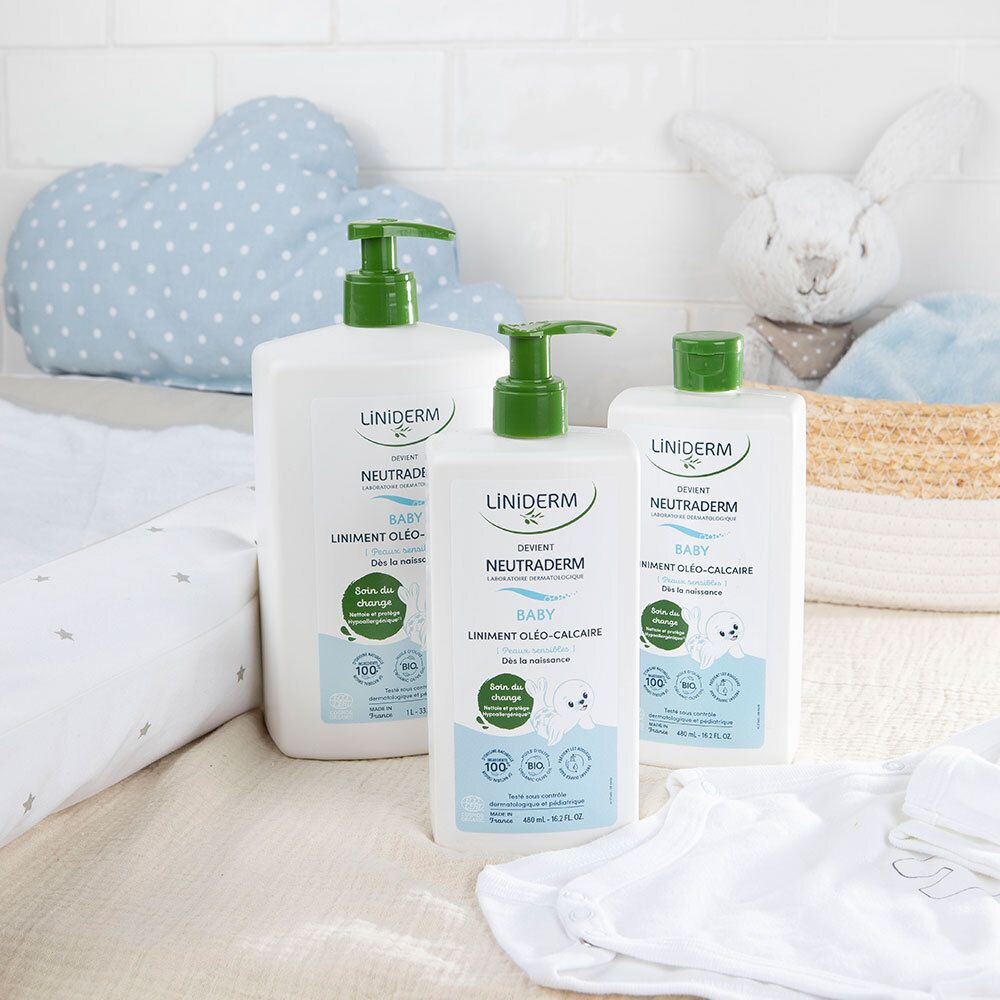 Drei Flaschen mit grünem Pumpkopf. Aufschrift: LINIDERM, NEUTRADERM BABY. Auf einer Wickelunterlage und neben Spielzeug.