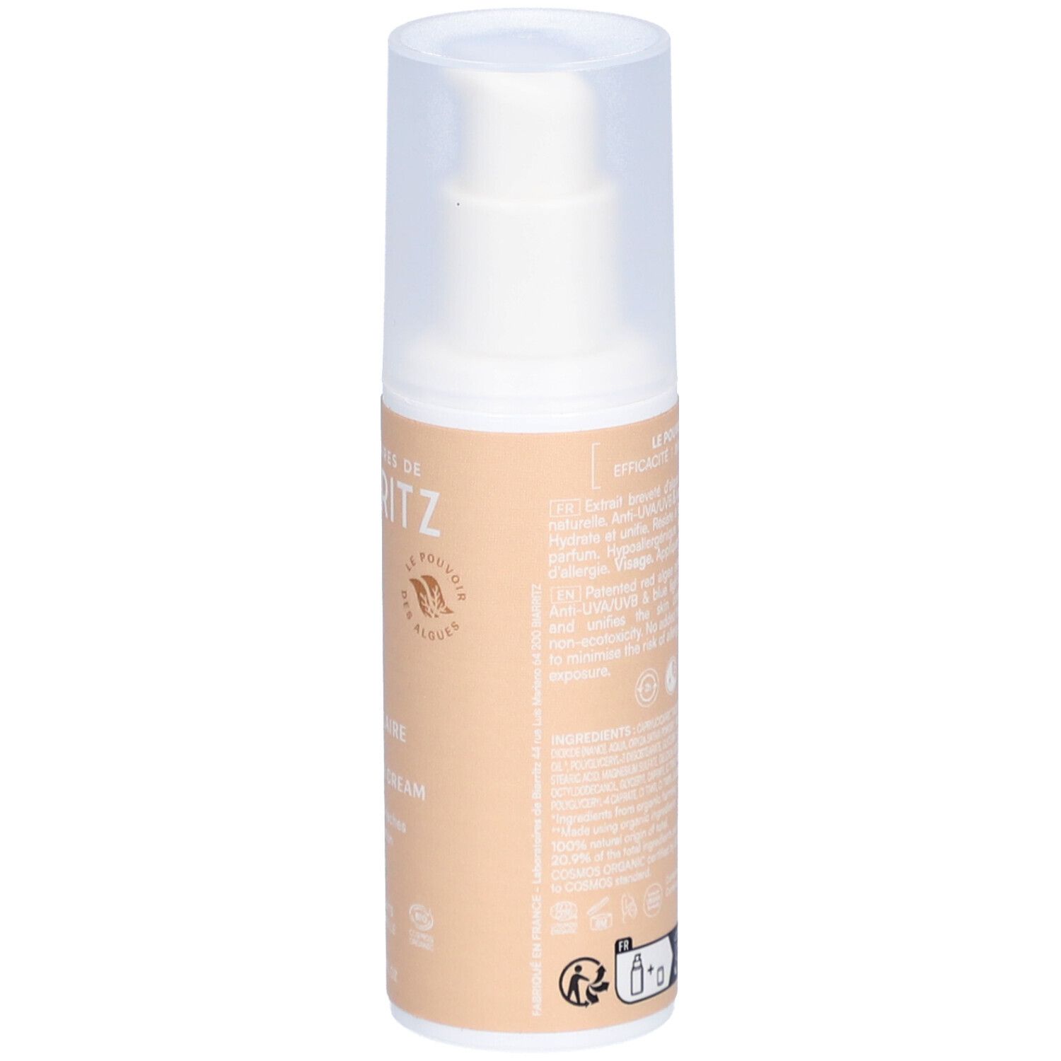 Dos du flacon de crème solaire teintée. Informations textuelles et logos. Fond beige.