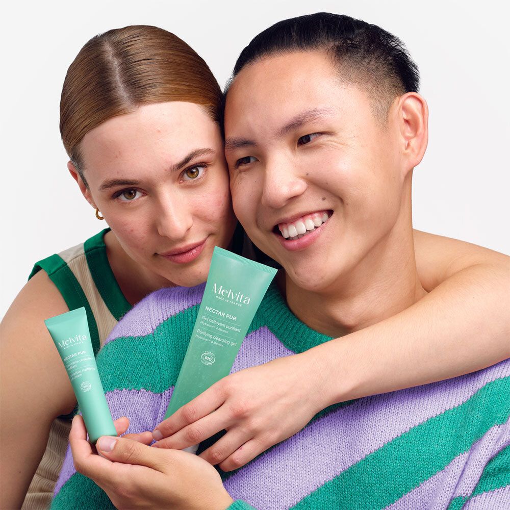 Zwei Personen halten Tuben. Aufschrift: MELVITA, NECTAR PUR, Gel-crème correcteur matifiant, Bio-Zertifizierung.