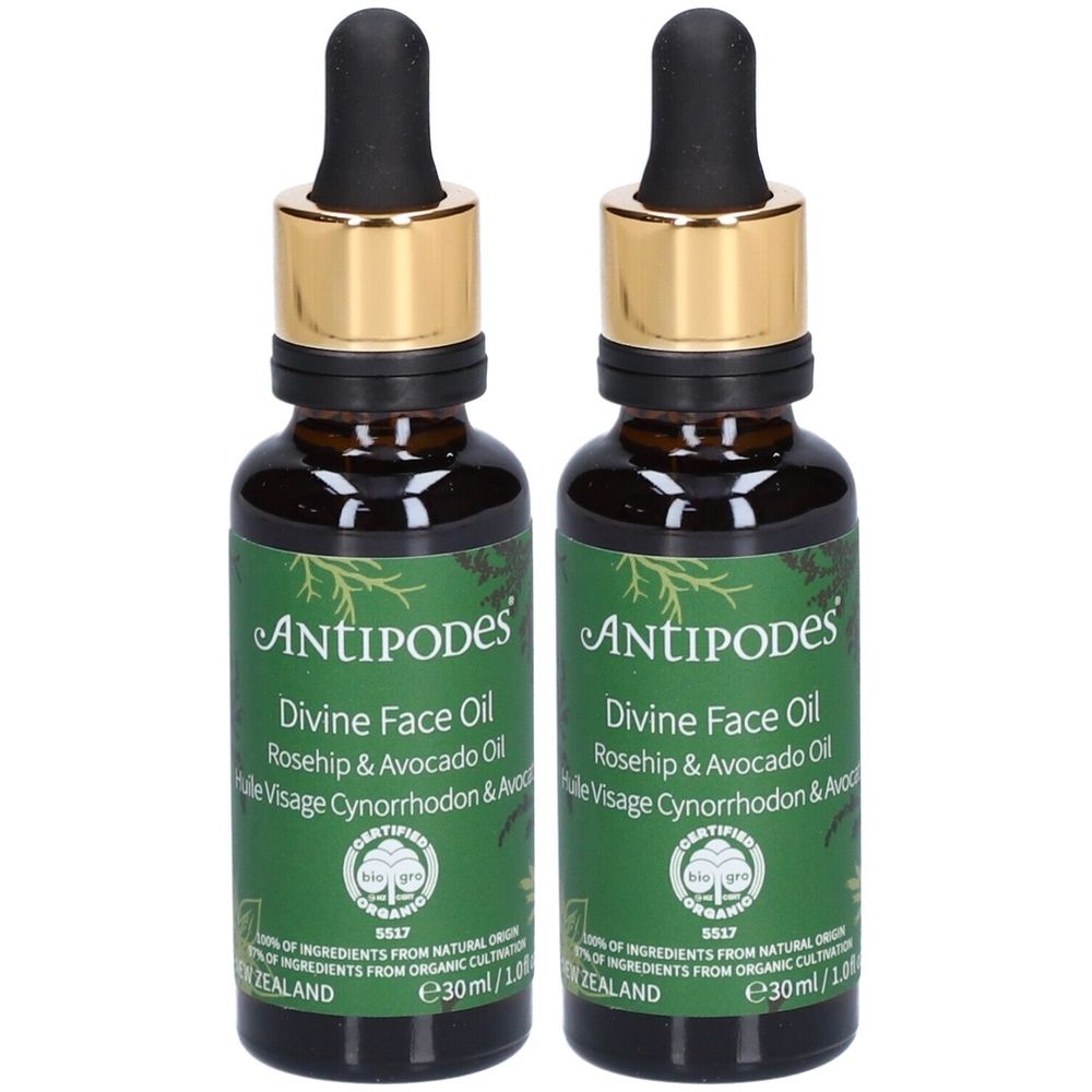 Deux flacons d'huile pour le visage Antipodes Divine avec pipettes. Étiquettes vertes avec nom du produit et certifications. Flacons en verre brun avec bouchons dorés.
