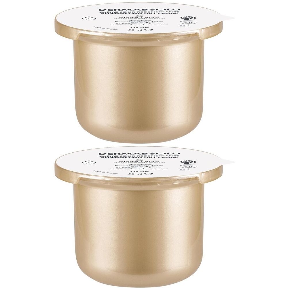 Deux pots dorés avec couvercles blancs. Inscription "DERMABSOLU" sur les couvercles.