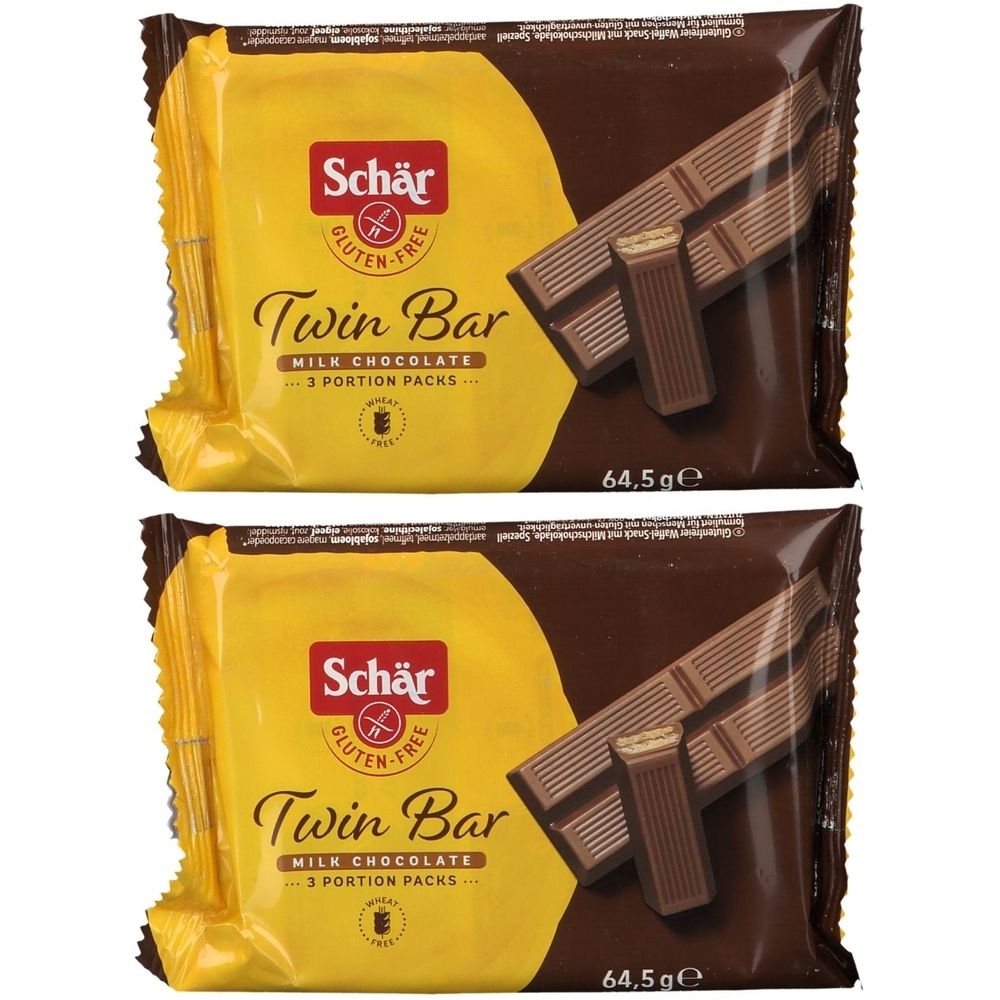 Zwei verpackte Schär Twin Bar glutenfrei. Gelbe Verpackung mit braunem Hintergrund. Aufschrift: Twin Bar, Milchschokolade, glutenfrei.
