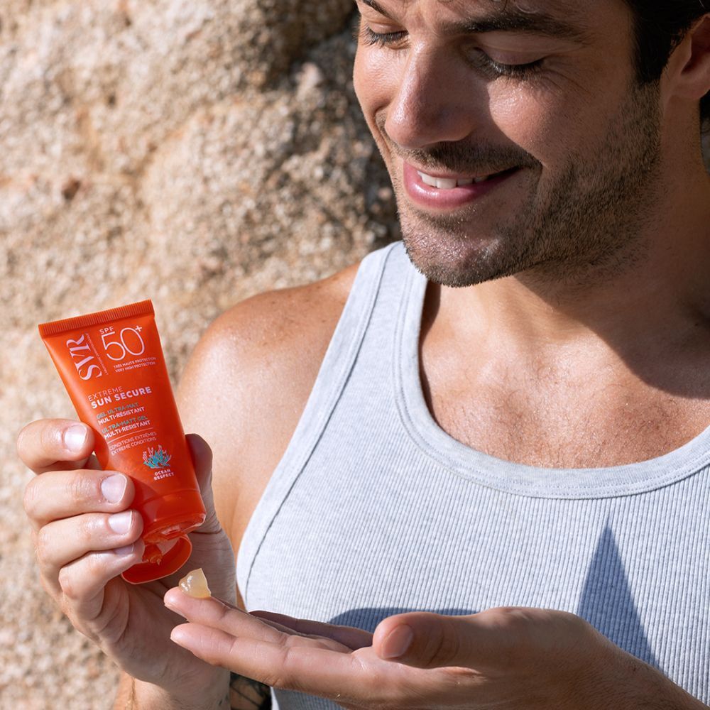 Tube SVR Sun Secure Extreme SPF 50+ sur du sable. Tube orange avec texte blanc. Inscription : Extreme Sun Secure, Gel Ultra-Mat.