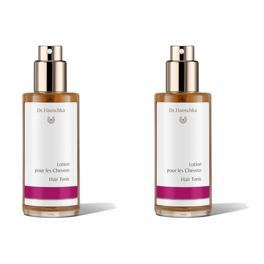 Zwei Flaschen mit Sprühkopf. Aufschrift: Dr. Hauschka, Lotion pour les Cheveux, Hair Tonic. Weißes Etikett mit pinkfarbenem Streifen.