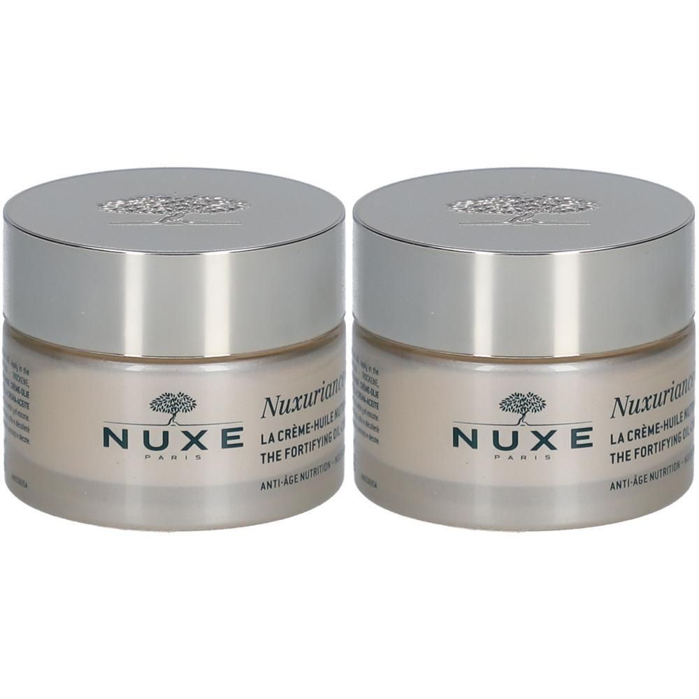 Deux pots de crème-huile Nuxuriance® Gold. Récipients en verre avec couvercles argentés. Inscription: Nuxe Paris.