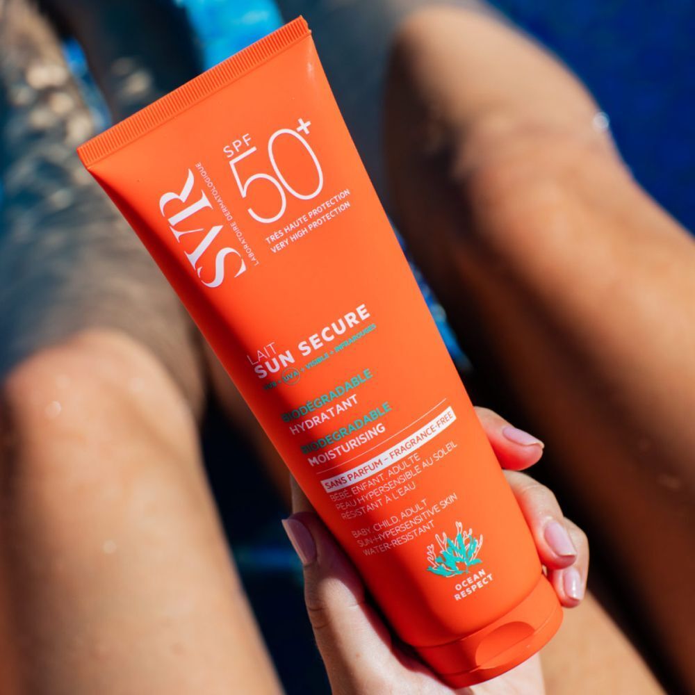 Tube orange de SVR Sun Secure Sonnenmilch SPF50+ tenue par une personne. Texte: Lait Sun Secure, SPF 50+, hydratant, fini invisible.