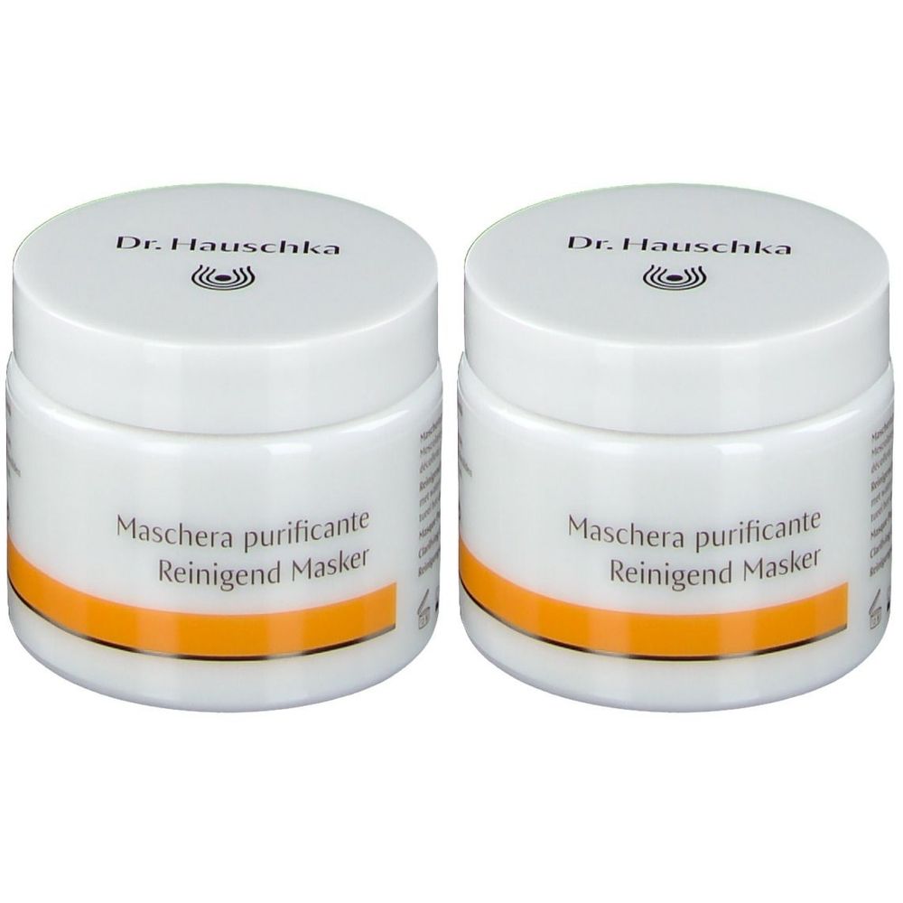 Zwei weiße Tiegel mit Deckel. Aufschrift: Dr. Hauschka, Maschera purificante, Reinigend Masker. Orangefarbener Streifen.