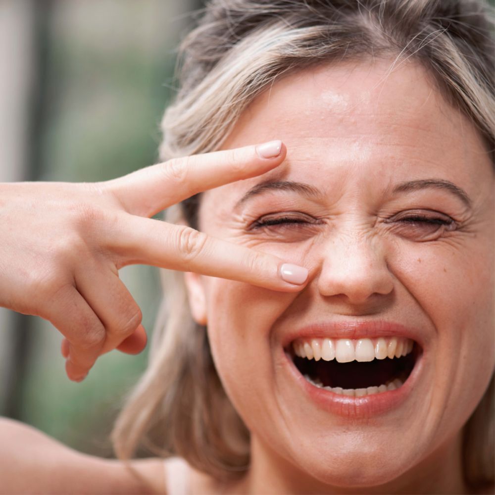 Femme avec les yeux fermés et la main devant le visage. Aucun produit visible.