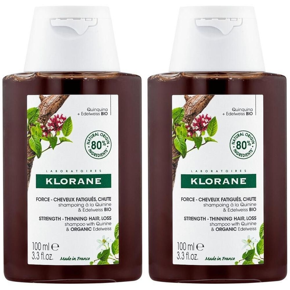 Zwei braune Flaschen KLORANE Shampoo. Aufkleber mit Text und Illustrationen. 80% natürliche Inhaltsstoffe. 100 ml.