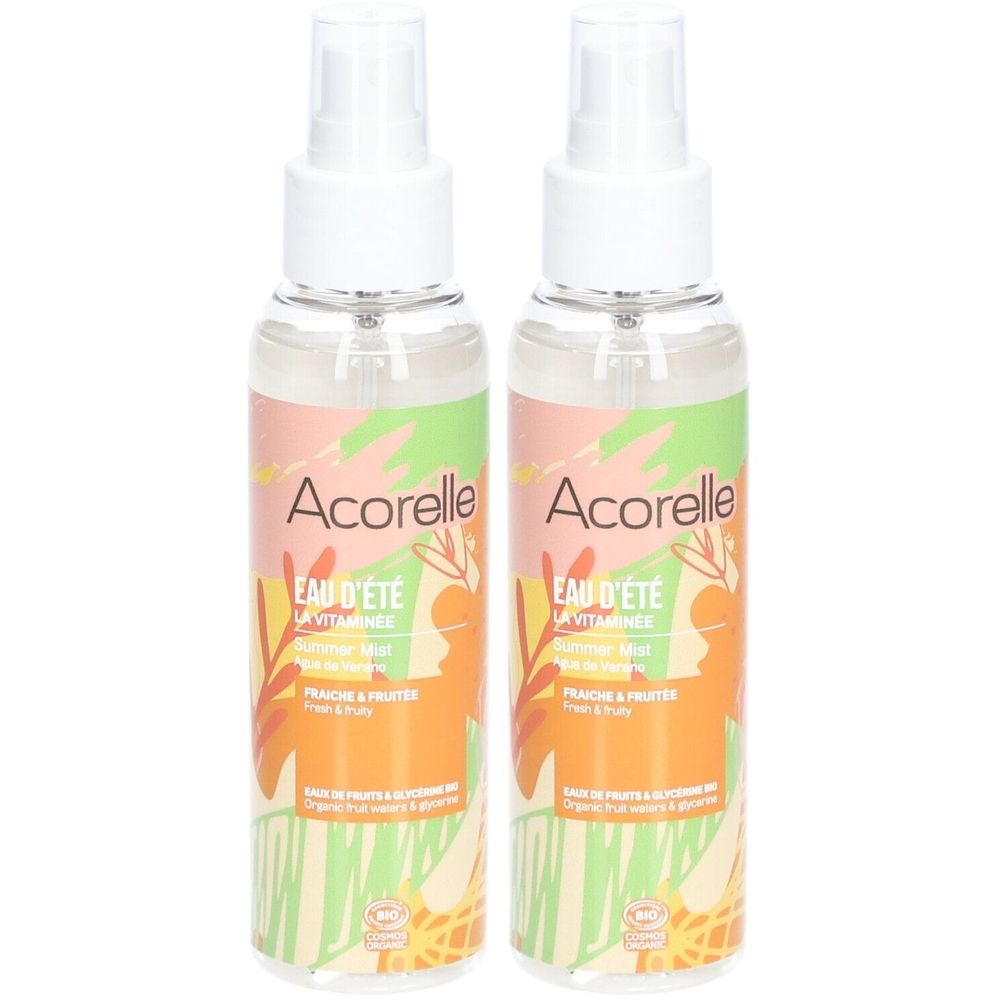 Zwei Sprühflaschen Acorelle Eau d'été. Weiße Sprühköpfe, transparente Flaschen mit farbigem Etikett. Aufschrift: Eau d'été, La Vitaminée.