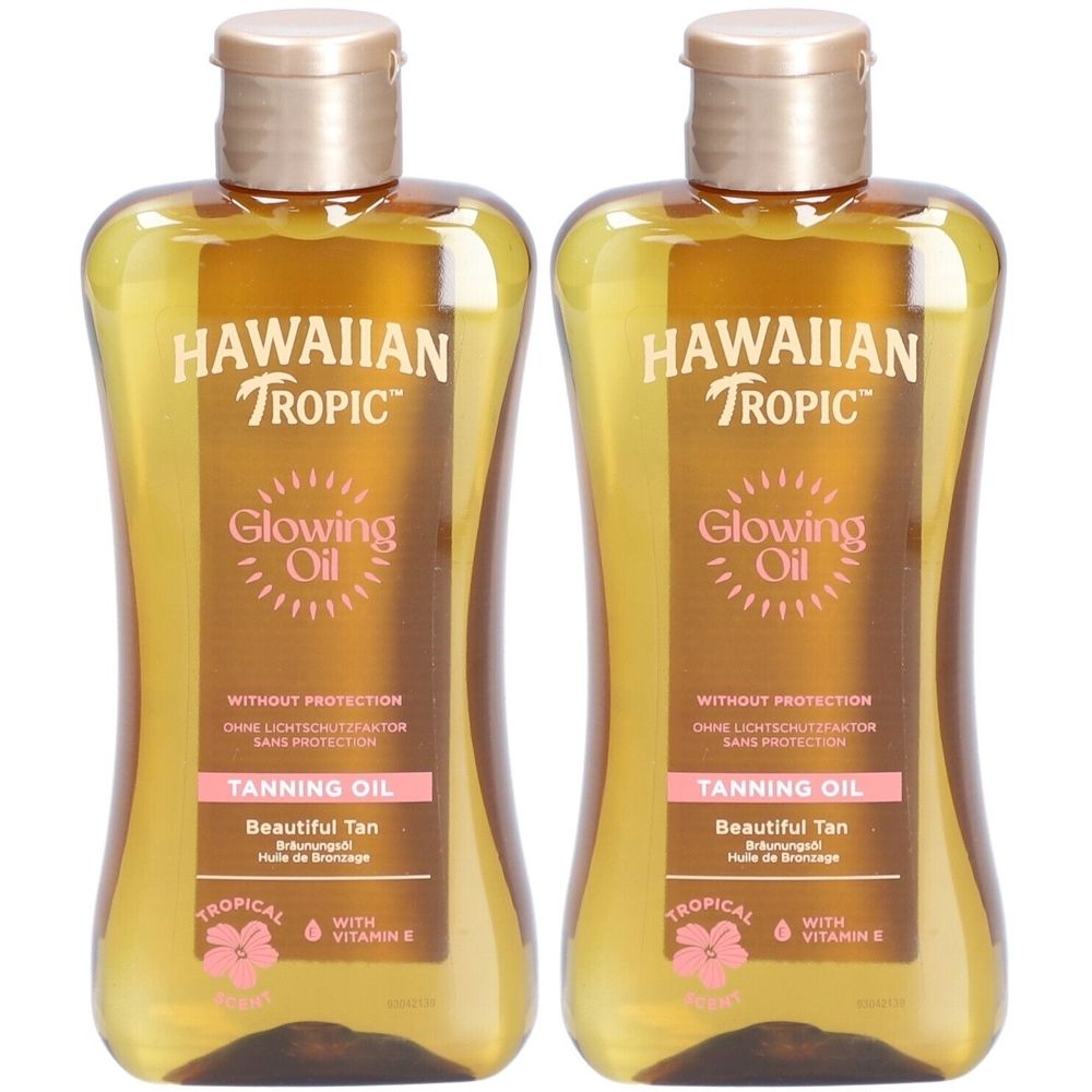 Deux flacons d'huile HAWAIIAN TROPIC Glowing Oil. Liquide doré dans des bouteilles transparentes avec bouchon doré. Texte: Tanning Oil, sans protection solaire.