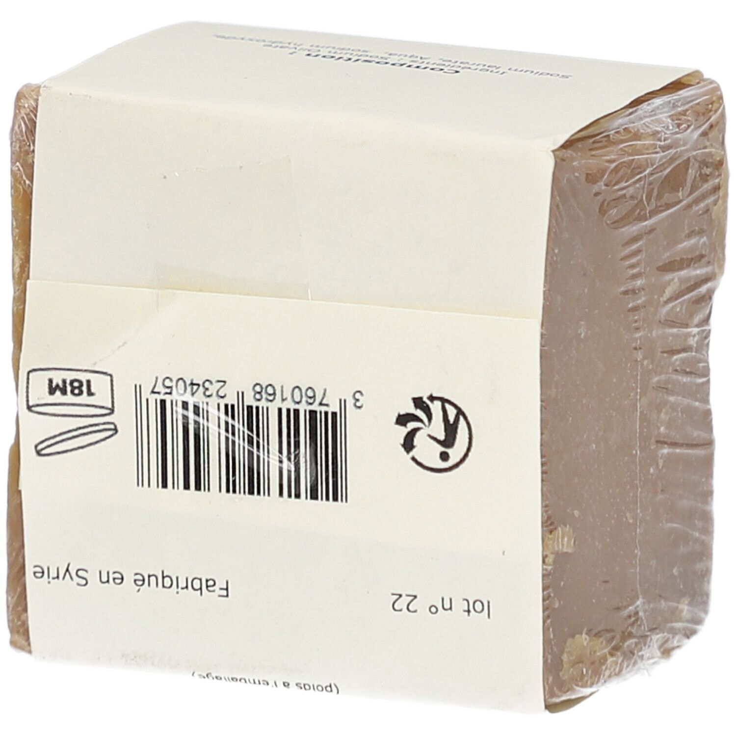 Bloc de savon emballé dans du papier et du film plastique. Verso avec code-barres, symboles de production et de recyclage. Fabriqué en Syrie.