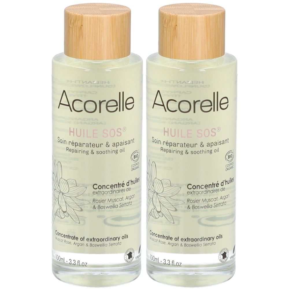 Deux flacons d'Acorelle Huile SOS. Liquide clair dans des flacons en verre avec bouchon en bois. Inscription: Soin réparateur & apaisant.