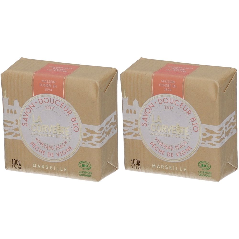 Deux savons carrés emballés dans du papier. Inscription : Savon Douceur Bio, Pêche de Vigne, Marseille. Avec certification bio.