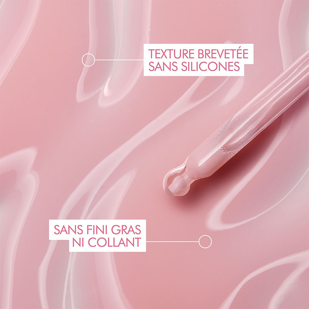 Nahaufnahme von Serum auf rosa Oberfläche. Text: Ohne Silikone, nicht fettend.