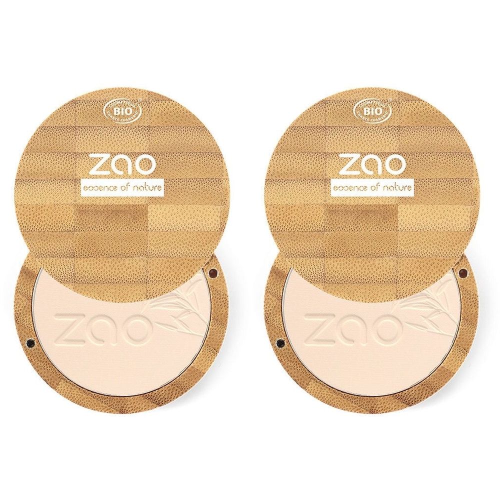 Zwei runde, offene Kompaktpuder-Dosen. Deckel aus Holz mit Logo und Bio-Zertifizierung. Puder hellbeige. Marke ZAO.