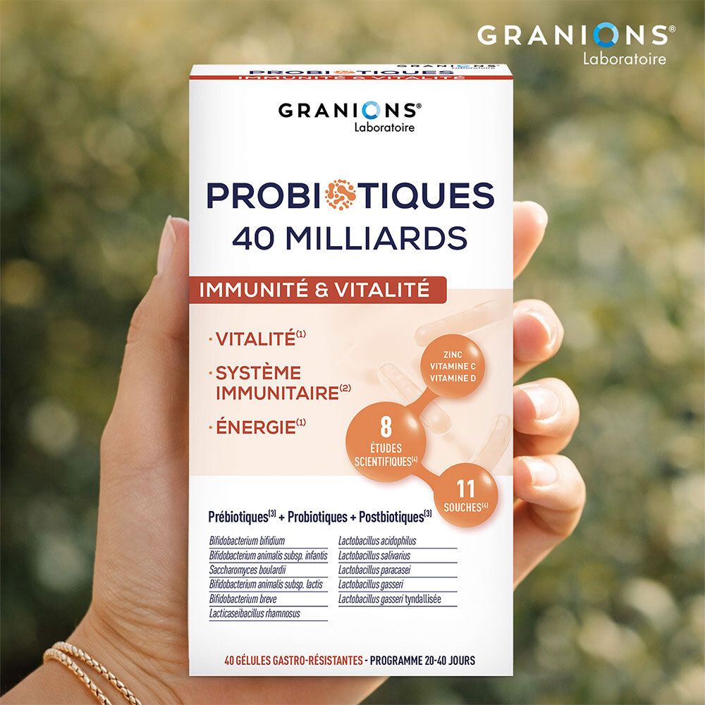 Main tenant la boîte Granions Probiotiques 40 Milliards sur fond flou.