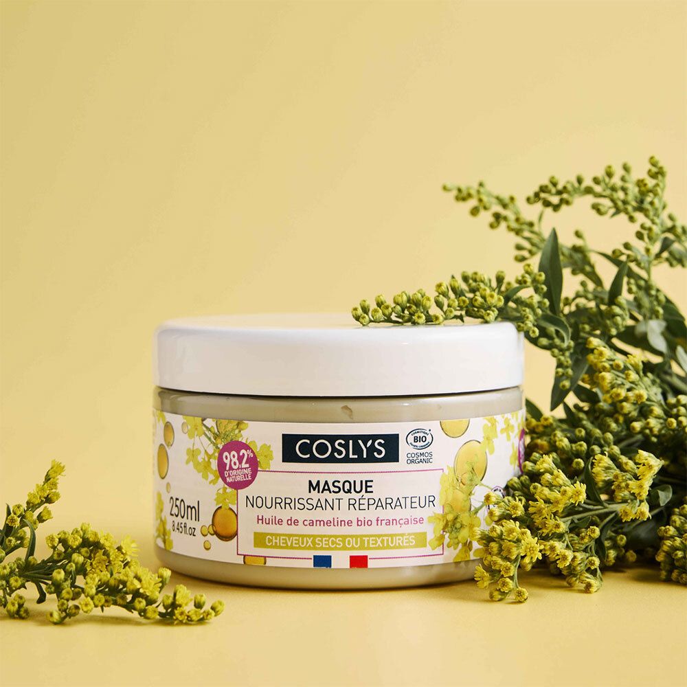 Runde Dose mit weißem Deckel. Aufschrift: Coslys Masque nourrissant réparateur. Mit gelben Blüten und Zweigen im Hintergrund.