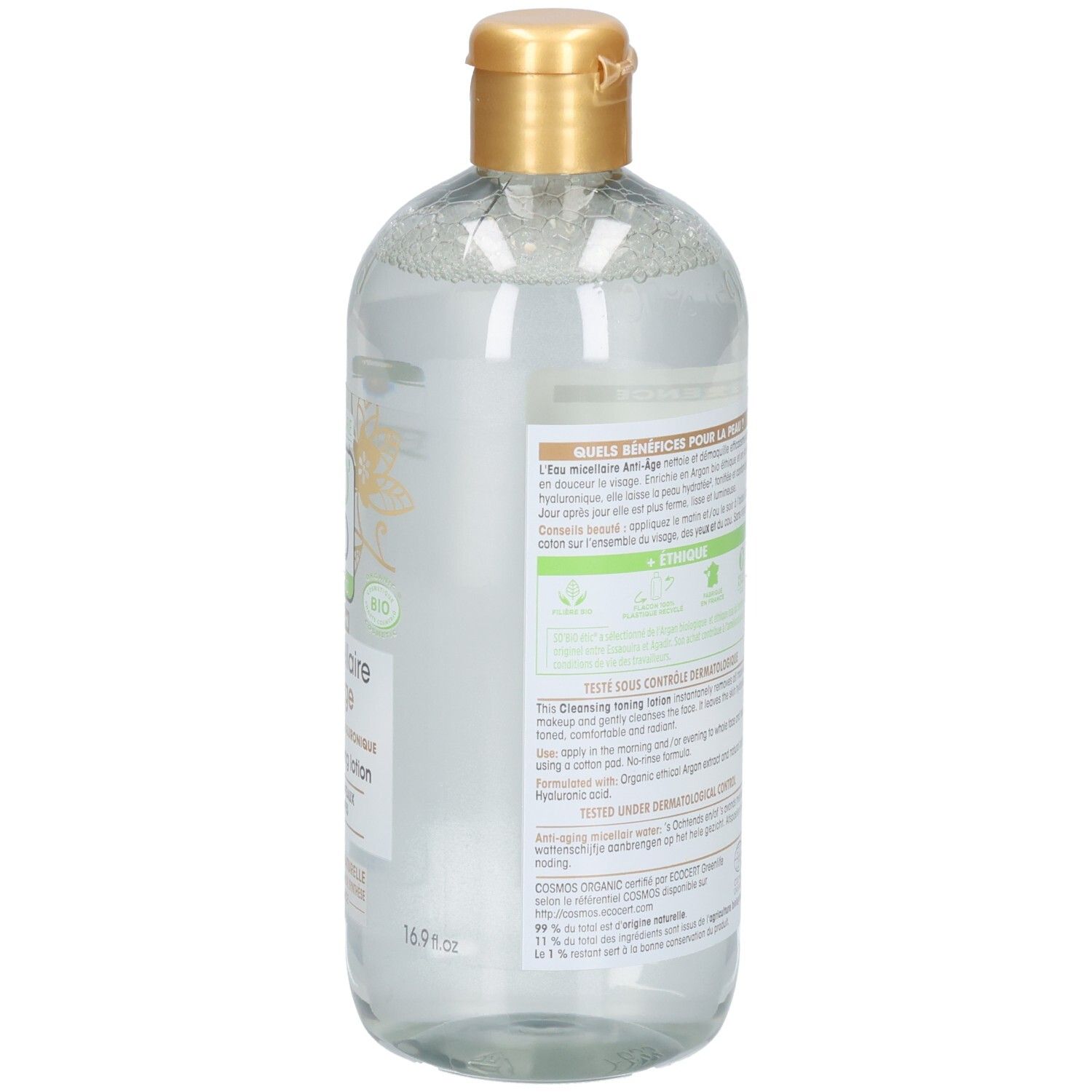 Rückansicht der Flasche. Etikett mit Text. Goldfarbener Verschluss. Transparente Flüssigkeit sichtbar.