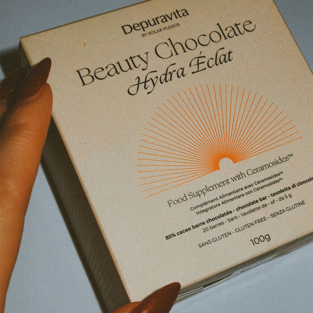 Nahaufnahme einer Hand, die eine Schachtel Depuravita Beauty Chocolate hält.