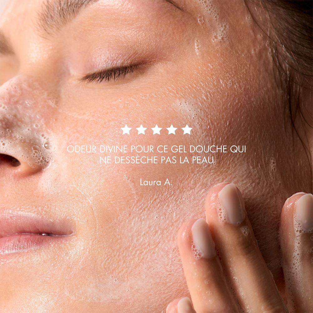Nahaufnahme eines Gesichts, das mit Schaum bedeckt ist. Fünf Sterne und Text: "ODEUR DIVINE POUR CE GEL DOUCHE QUI NE DÉSSÈCHE PAS LA PEAU".