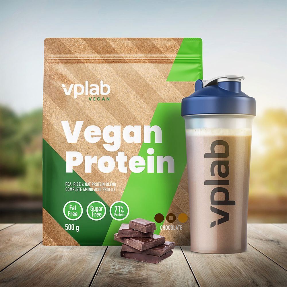 Vplab Vegan Protein Beutel und Shaker neben Schokoladenstücken auf einem Holztisch. Hintergrund: verschwommene Natur.