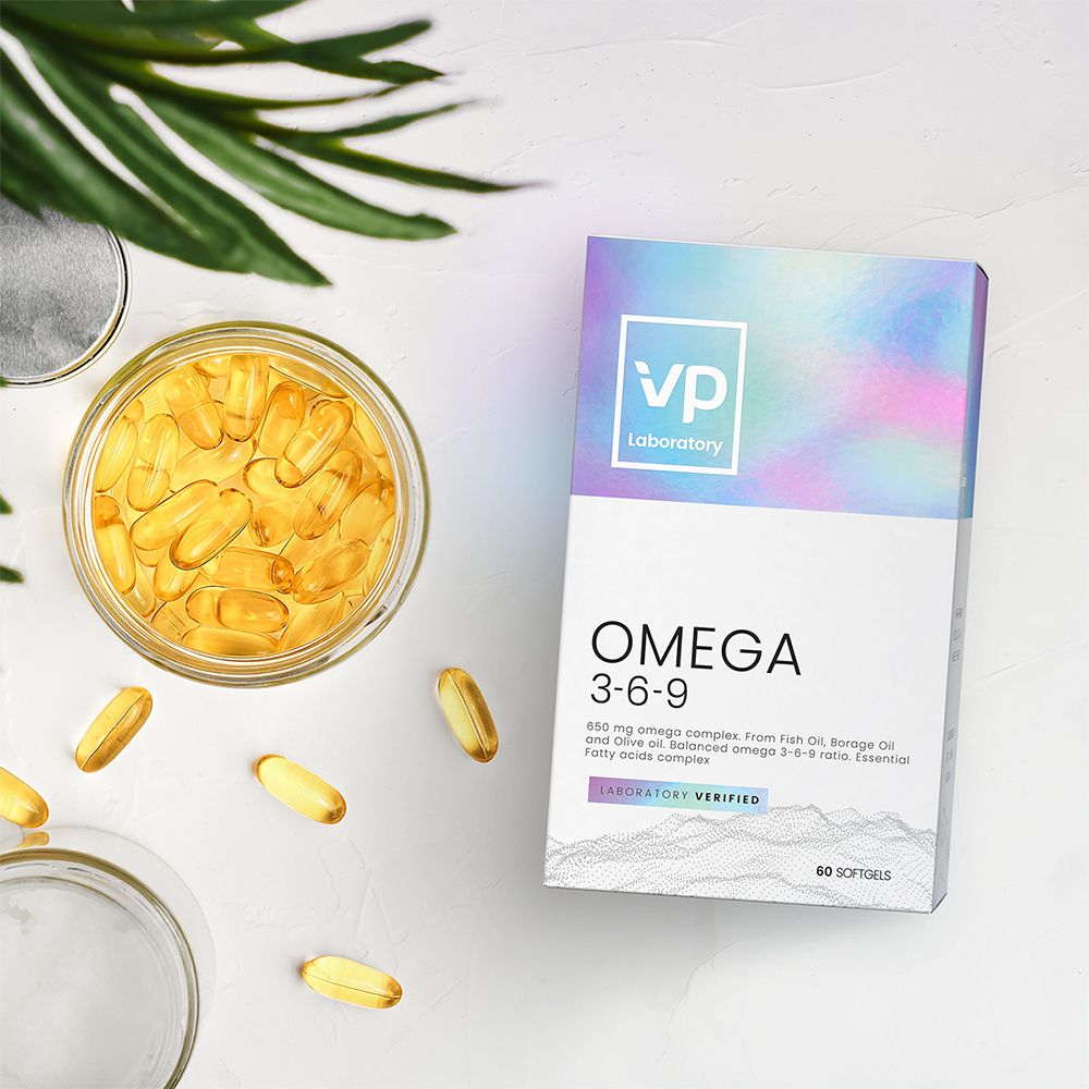 VP Laboratory Omega 3-6-9-Verpackung neben einem Glas Softgels. Grünpflanze im Hintergrund.