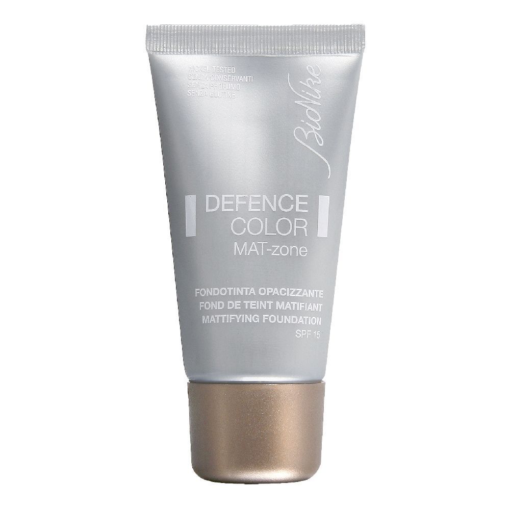 Silberfarbene Tube mit braunem Verschluss. Aufschrift: DEFENCE COLOR MAT-zone. Fondotinta Opacizzante. SPF 15.