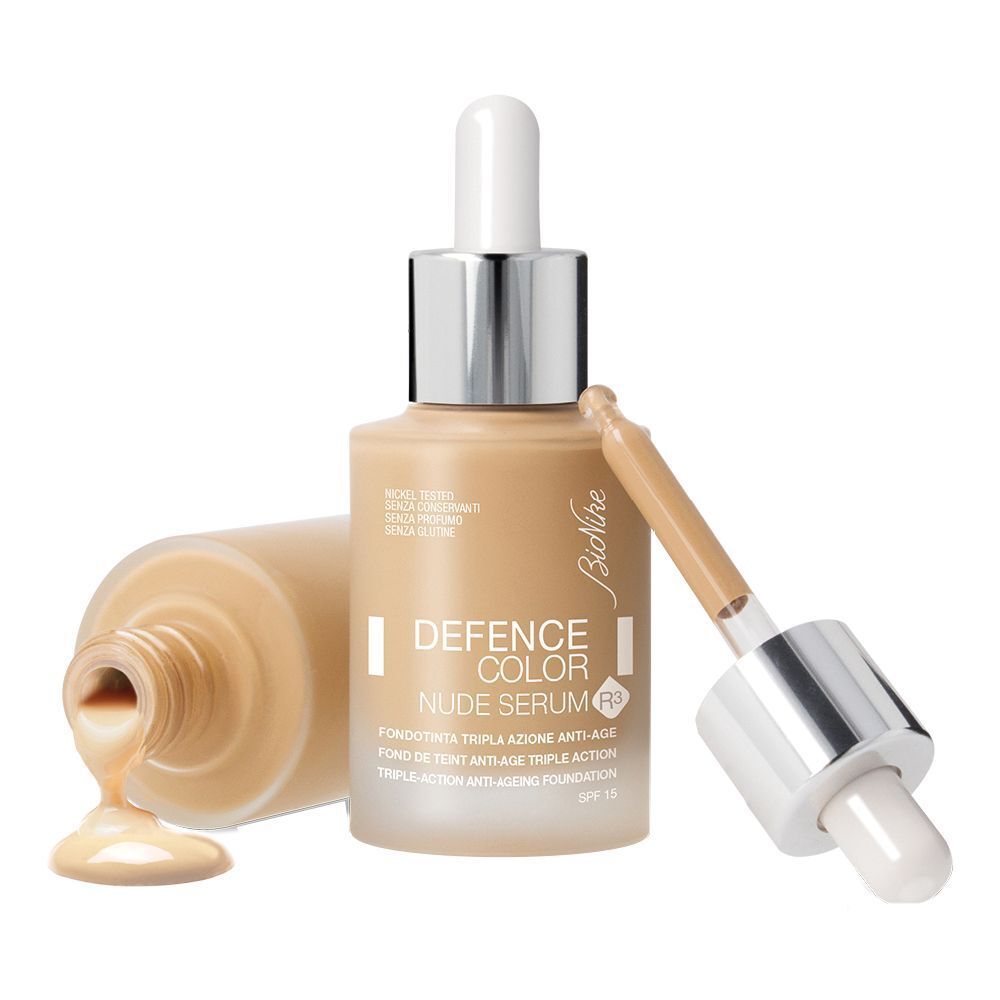 Flacon de sérum avec pipette. Nom du produit : DEFENCE COLOR Nude Serum R3. Liquide beige coulant du flacon.