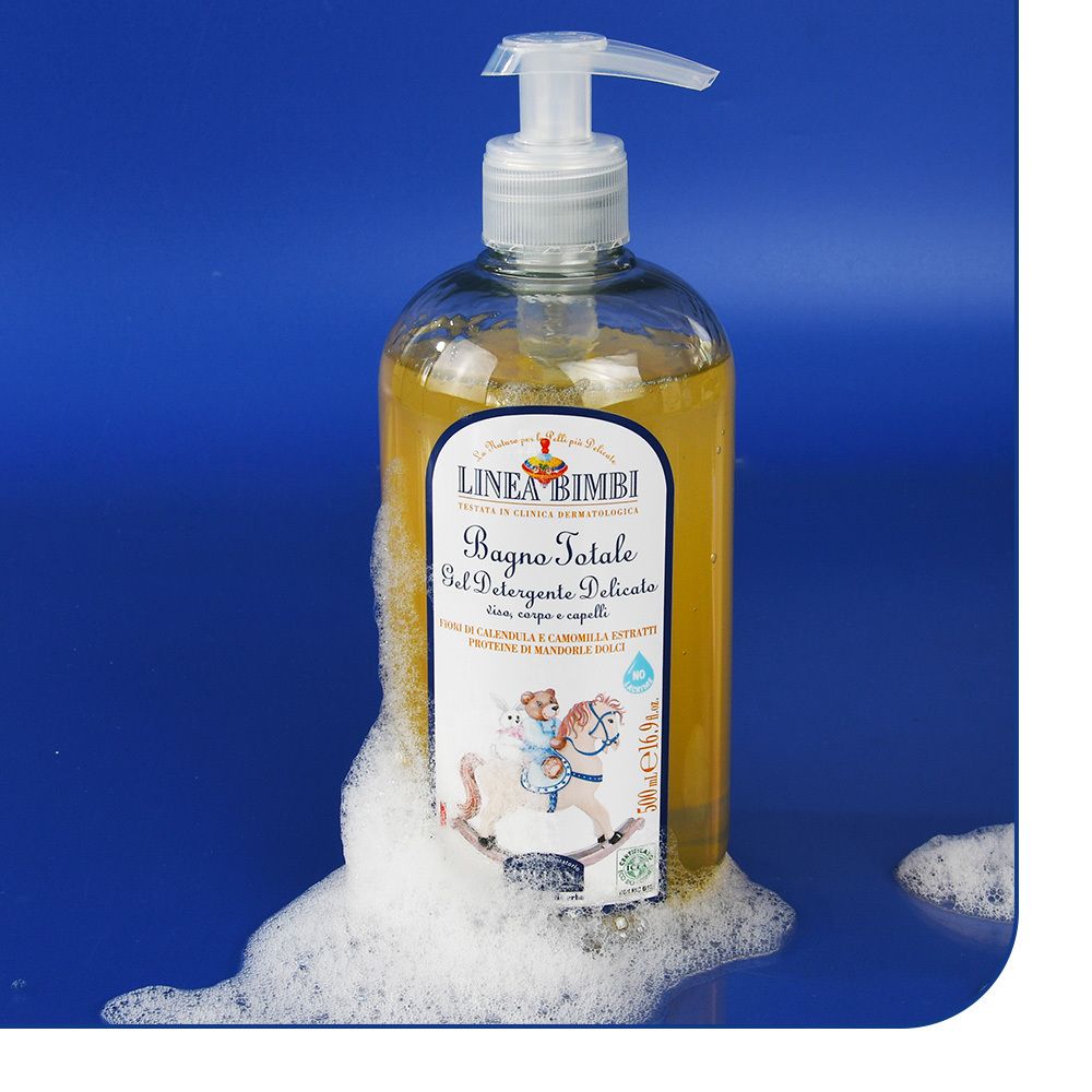 Flacon de gel nettoyant avec pompe, entouré de mousse. Inscription : LINEA BIMBI, Bagno Totale, Gel Detergente Delicato. Enfant sur cheval à bascule.