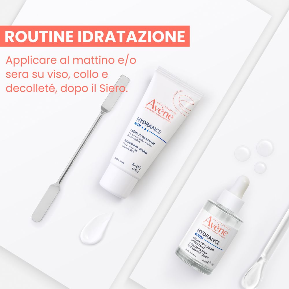 Avene Hydrance Feuchtigkeitscreme und konzentriertes Serum auf weißem Hintergrund mit Spateln und Wassertropfen.