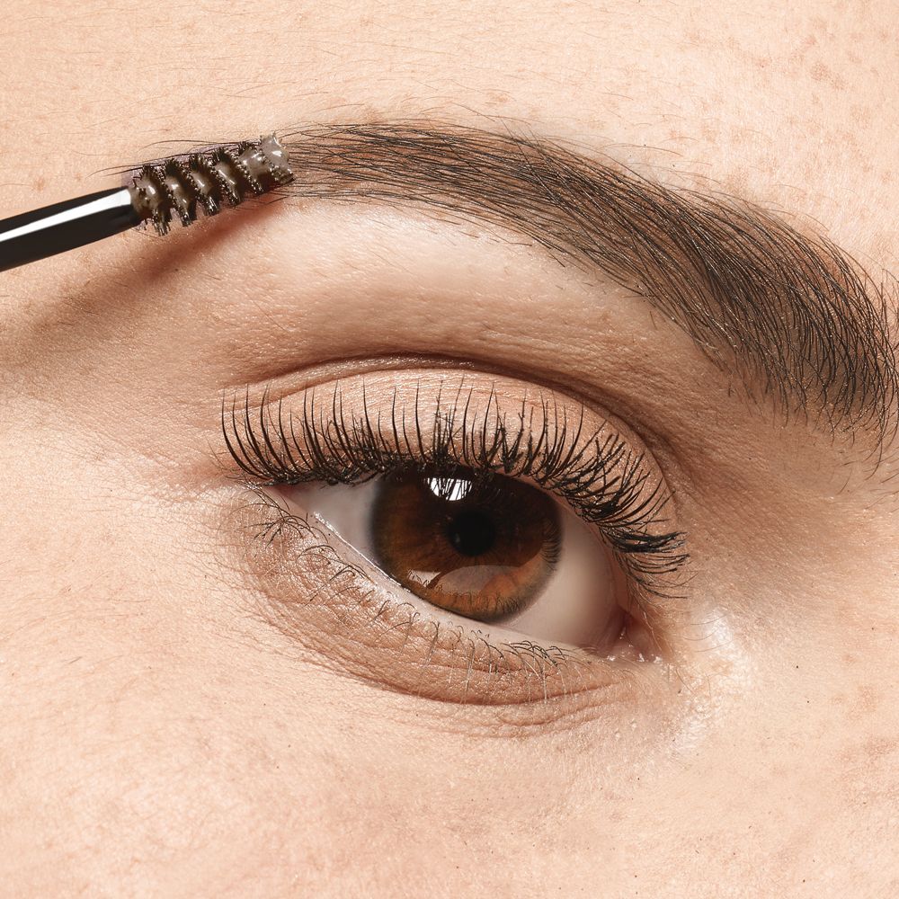 Œil avec sourcil brossé avec un applicateur de mascara. Yeux bruns.