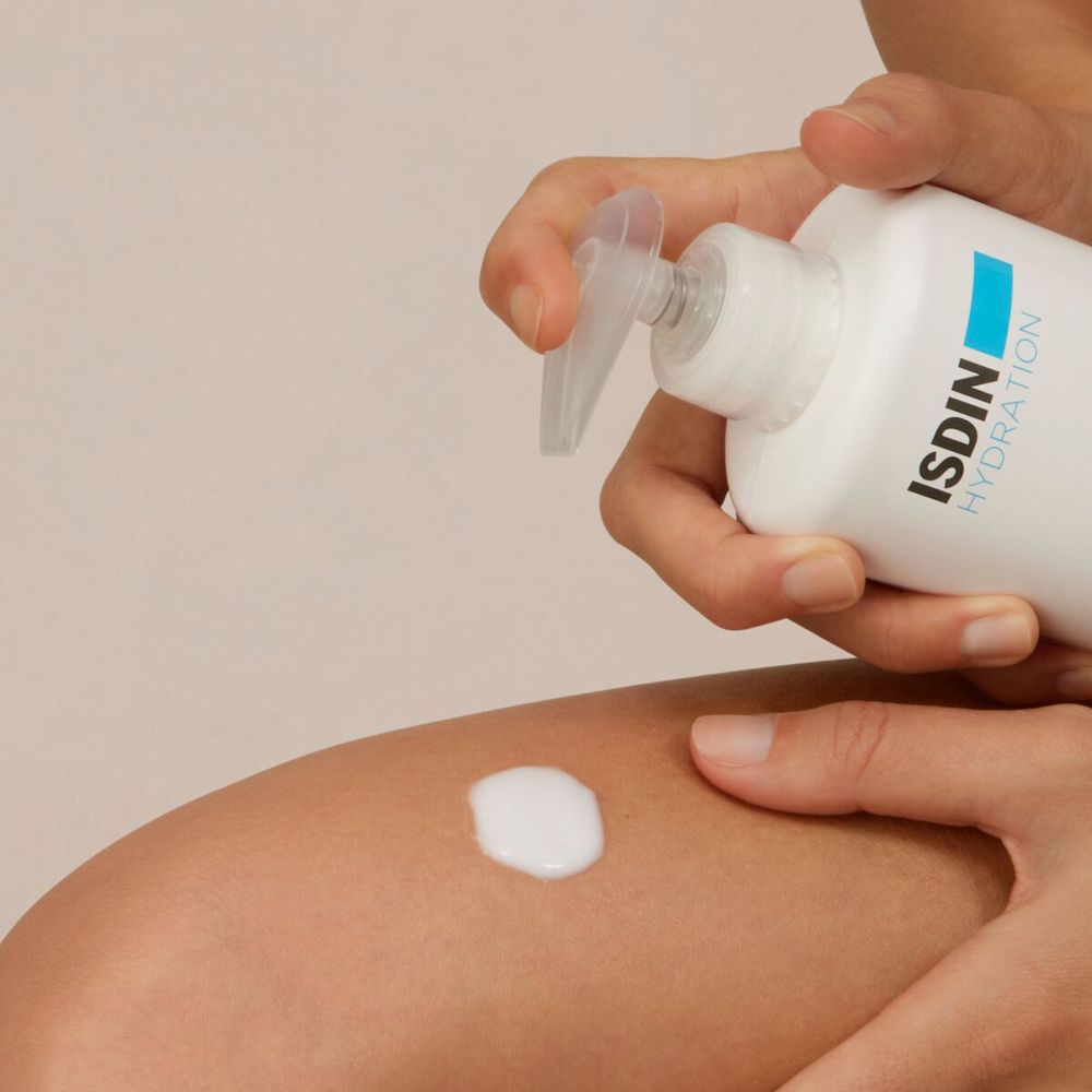 Lotion blanchâtre appliquée sur une jambe. Flacon pompe en arrière-plan.