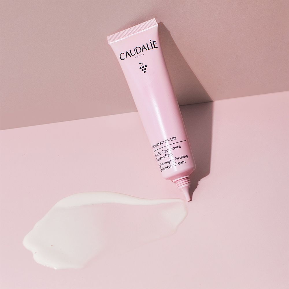 Rosa Tube mit CAUDALÍE-Logo und Produktbezeichnung. Creme-Klecks daneben. Hintergrund: Rosa.