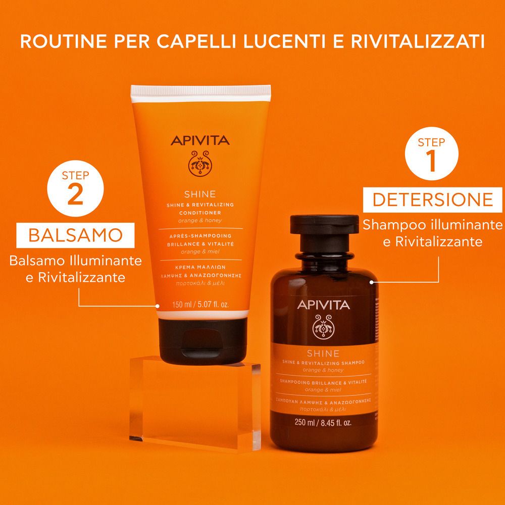Deux flacons sur fond orange. Un tube et une bouteille avec inscription: APIVITA SHINE. Texte: Routine per capelli lucenti e rivitalizzati.