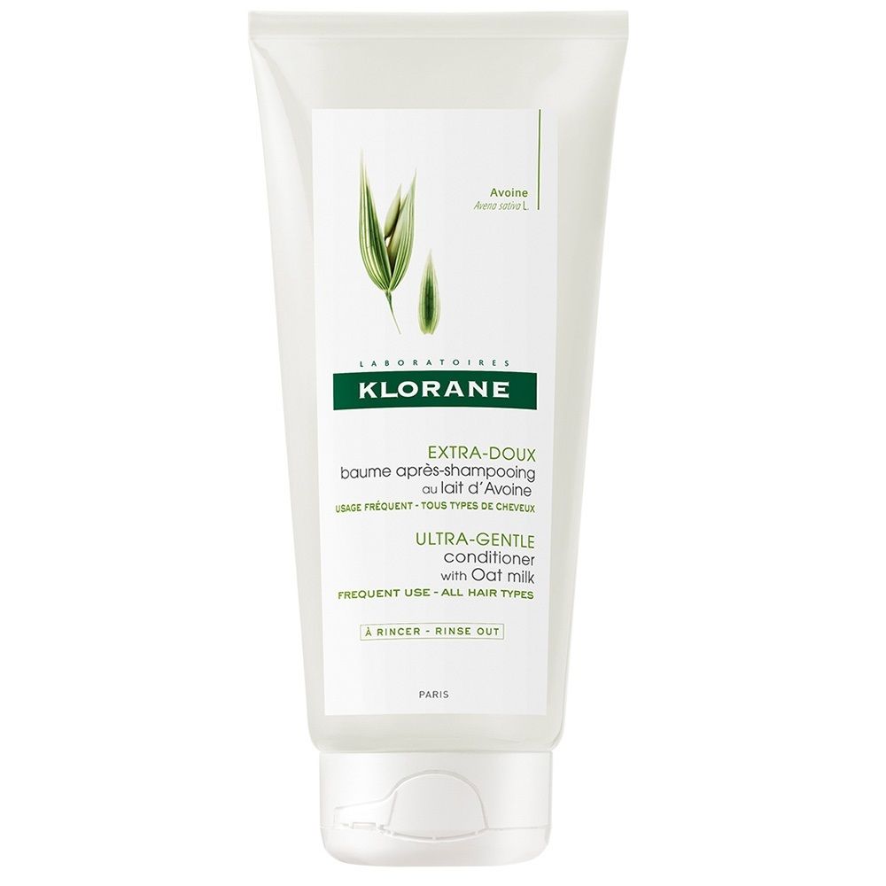Tube de baume blanc. Inscriptions: KLORANE, EXTRA-DOUX, baume après-shampooing, ULTRA-GENTLE conditioner with Oat milk. Illustration végétale.