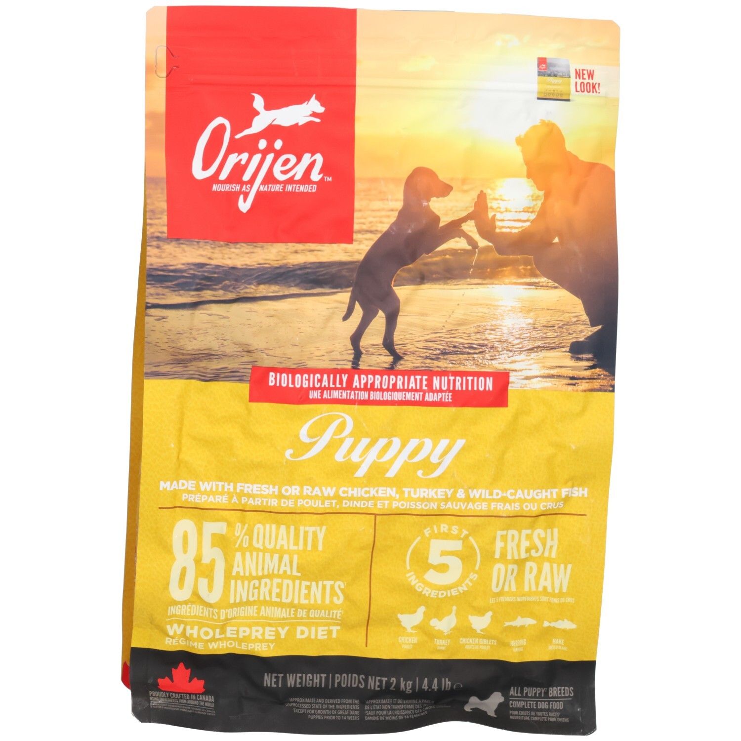 Orijen Puppy Hundefutter, 2kg Beutel. Vorderseite mit Bild eines Mannes und Welpen am Strand.