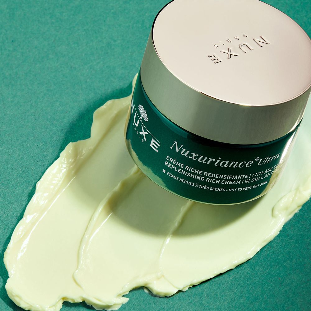 Pot NUXE Nuxuriance Ultra sur crème. Vert, couvercle doré. Texte: Nuxuriance Ultra, crème, Peaux sèches à très sèches.